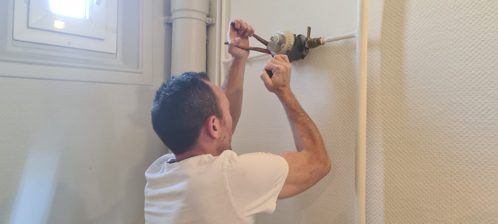 Homme réparant un radiateur avec des pinces.